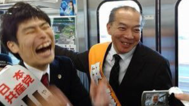 電車内で候補者名入りタスキをかけて爆笑する山添拓と伊藤岳